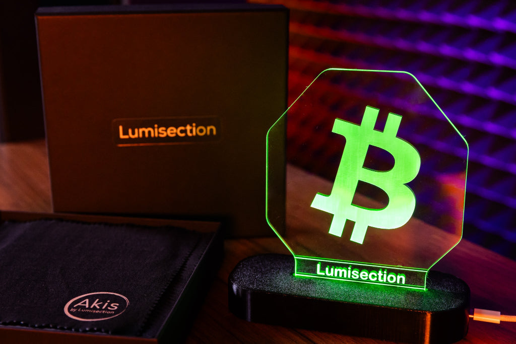 Lumisection Bitcoin-themed LED sign with Akis branded cloth in the background