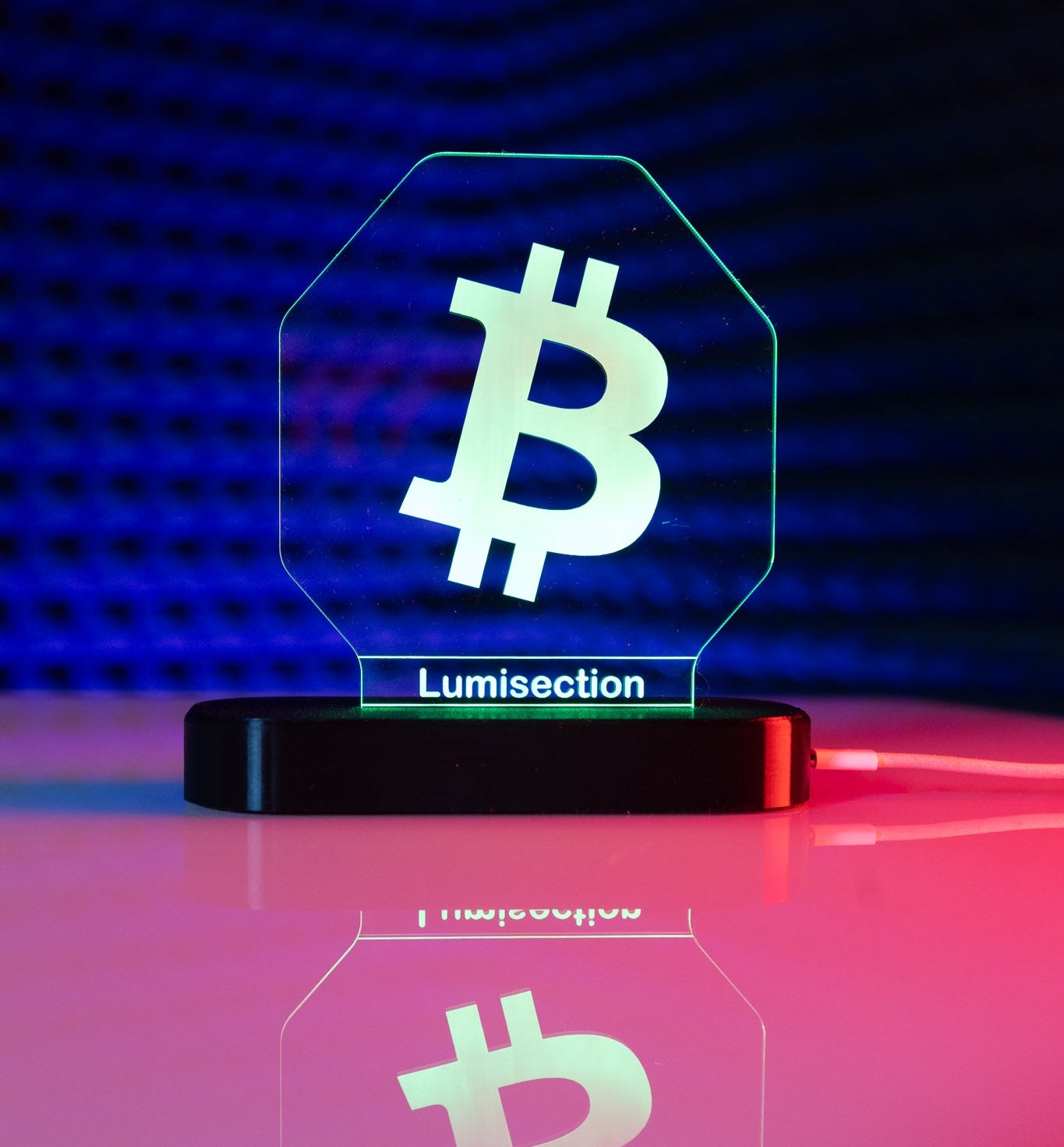 Lumisection Bitcoin-themed LED lamp on a reflective surface with a dark blue gradient background.