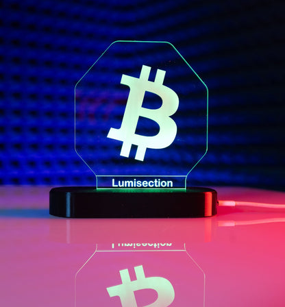 Lumisection Bitcoin-themed LED lamp on a reflective surface with a dark blue gradient background.